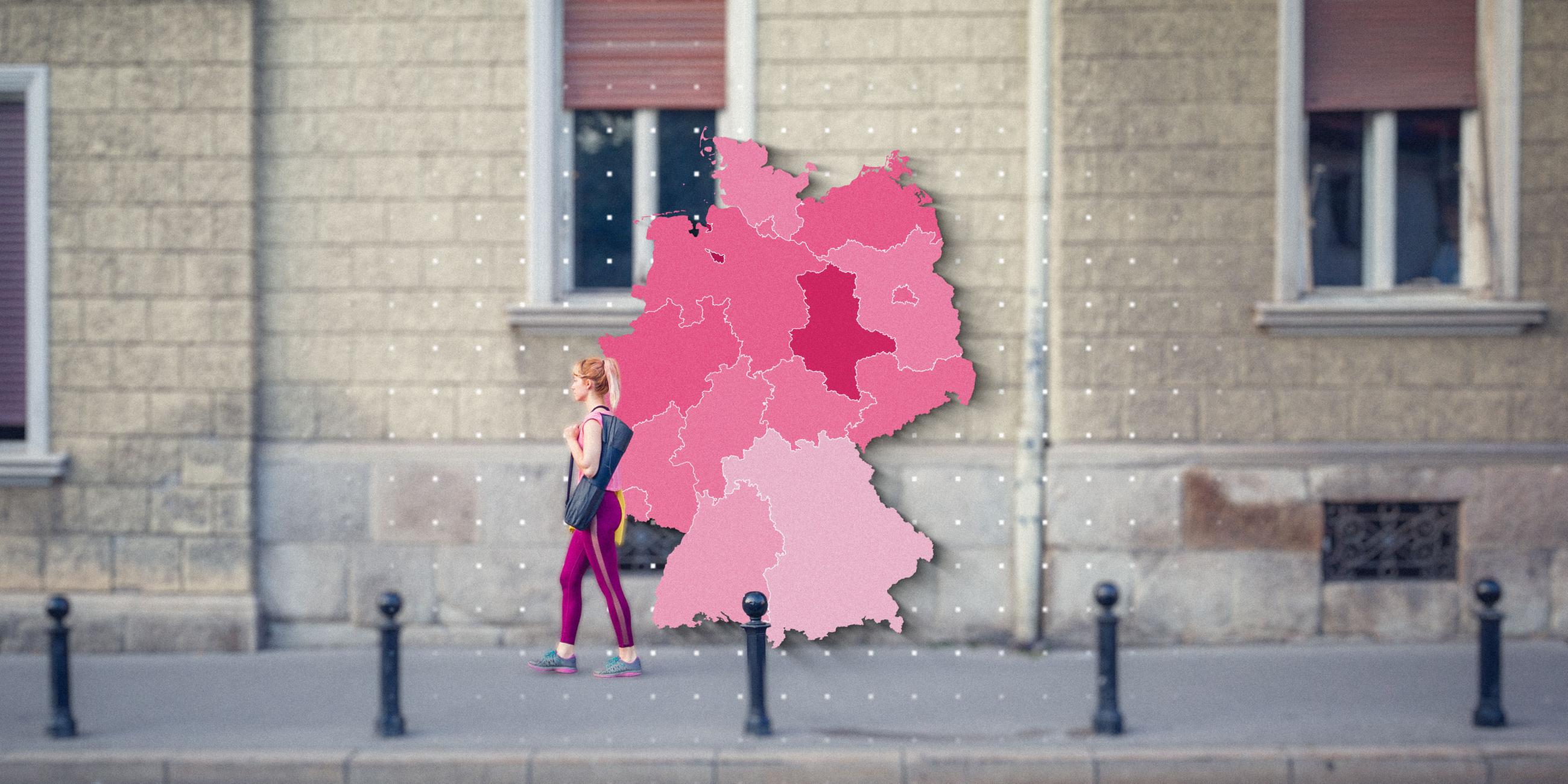 Eine Frau läuft vor der Fassade eines Gebäudes entlang. Drauf ist die Grafik einer Deutschlandkarte zu sehen.