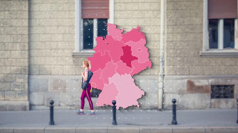 Eine Frau läuft vor der Fassade eines Gebäudes entlang. Drauf ist die Grafik einer Deutschlandkarte zu sehen.
