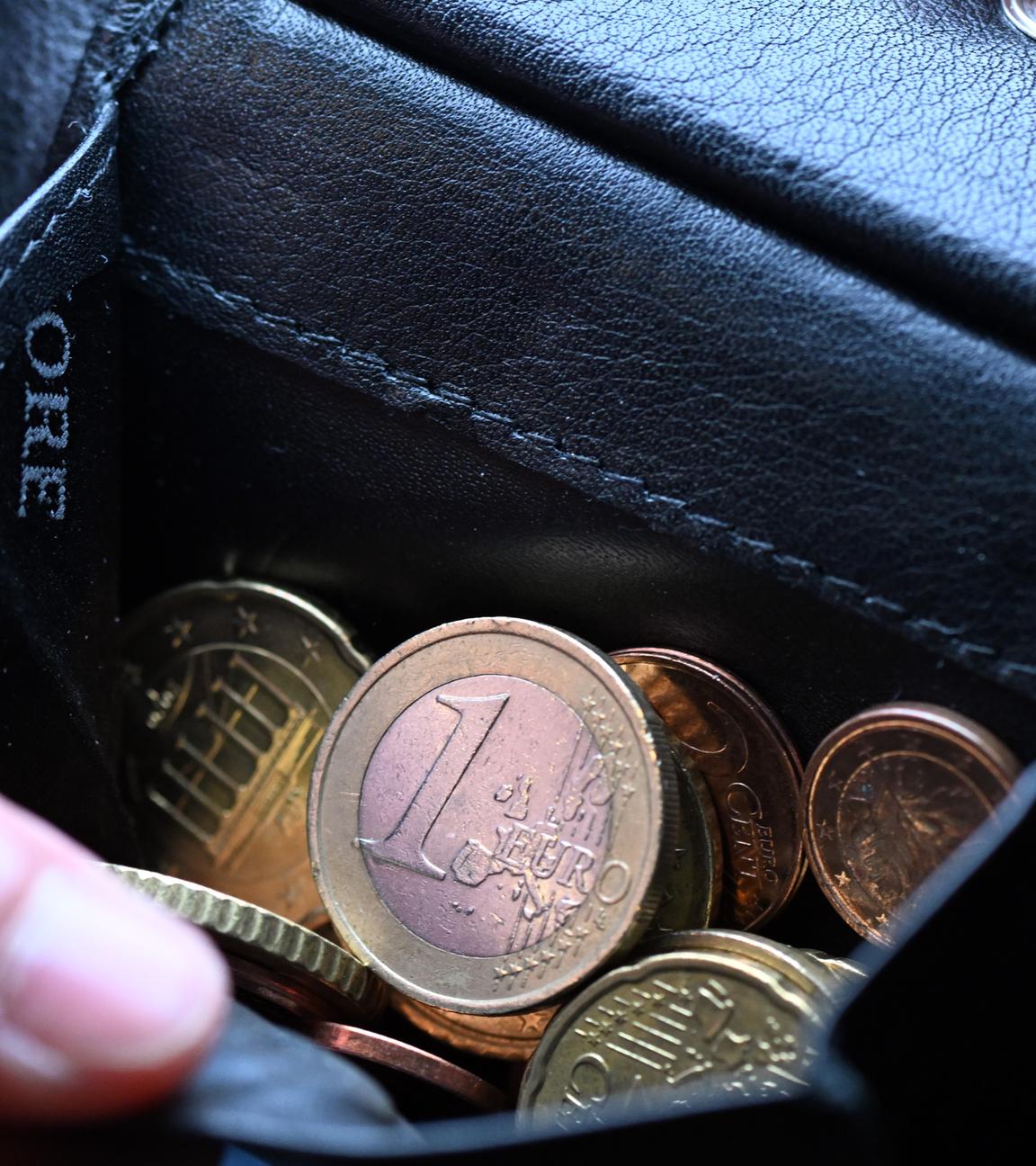 Nordrhein-Westfalen, Köln: Eine Hand greift in einen Geldbeutel mit Münzen.