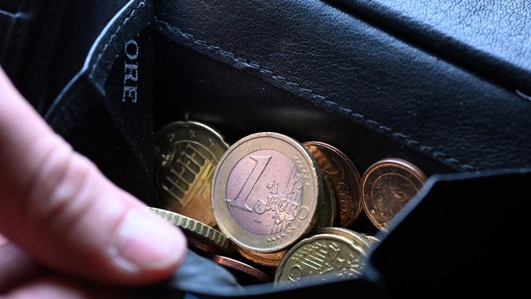Nordrhein-Westfalen, Köln: Eine Hand greift in einen Geldbeutel mit Münzen.