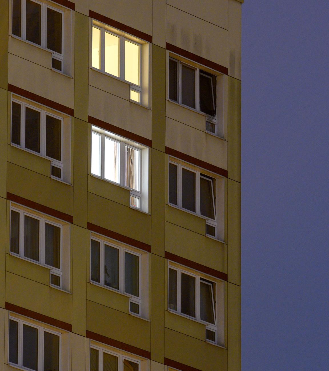 Einzelne Lichter brennen in den Fenstern eines Wohnhochhauses der Landeshauptstadt von Sachsen-Anhalt.