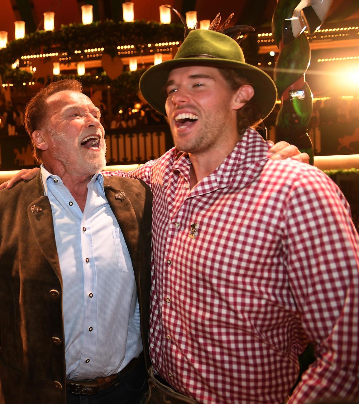 26.09.2025, Bayern, München: Arnold Schwarzenegger und sein Sohn Christopher Schwarzenegger stehen im Marstall-Festzelt auf der Bühne und dirigieren.