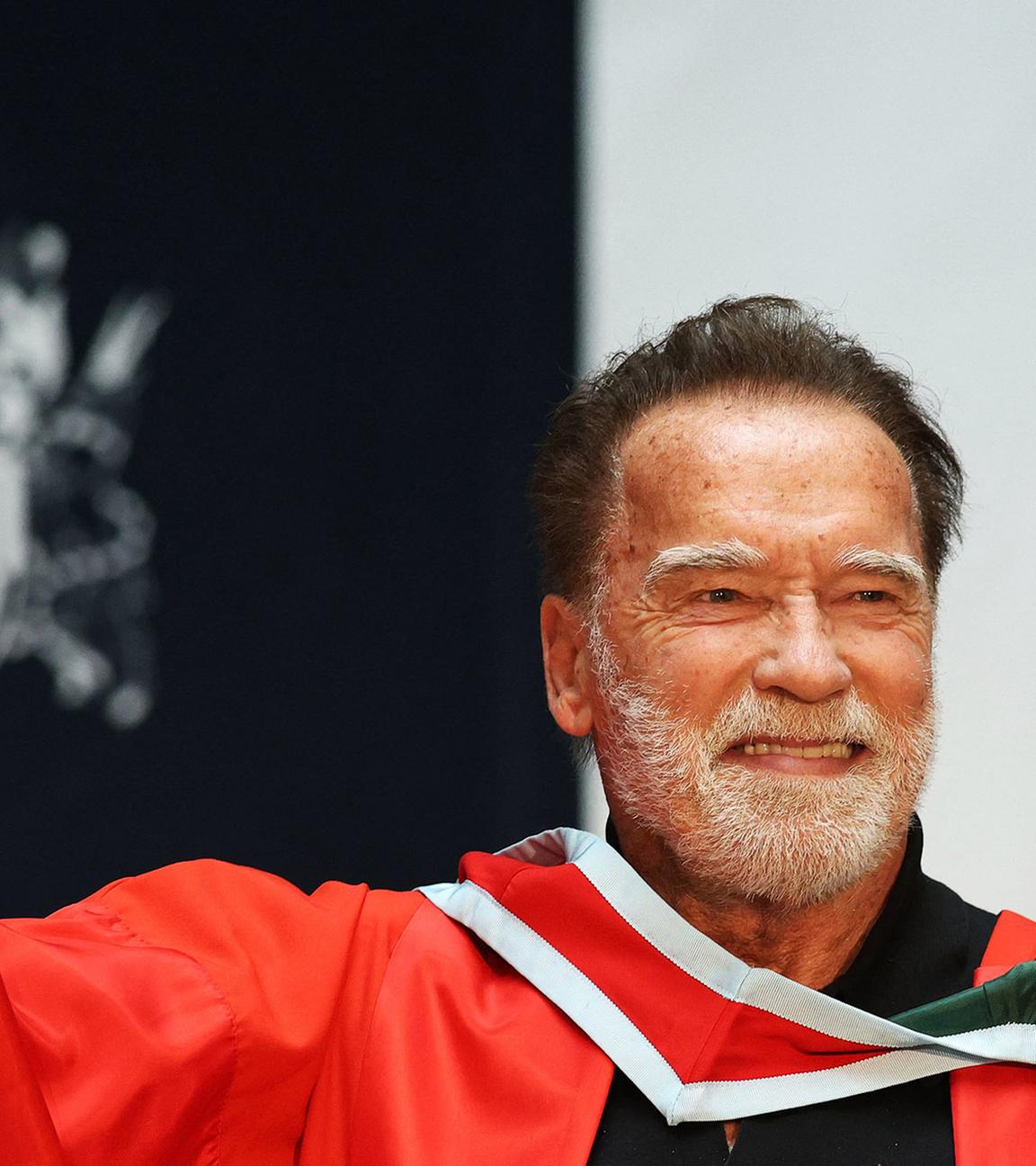 Arnold Schwarzenegger hält sein Doktortitel-Diplom in der Hand.
