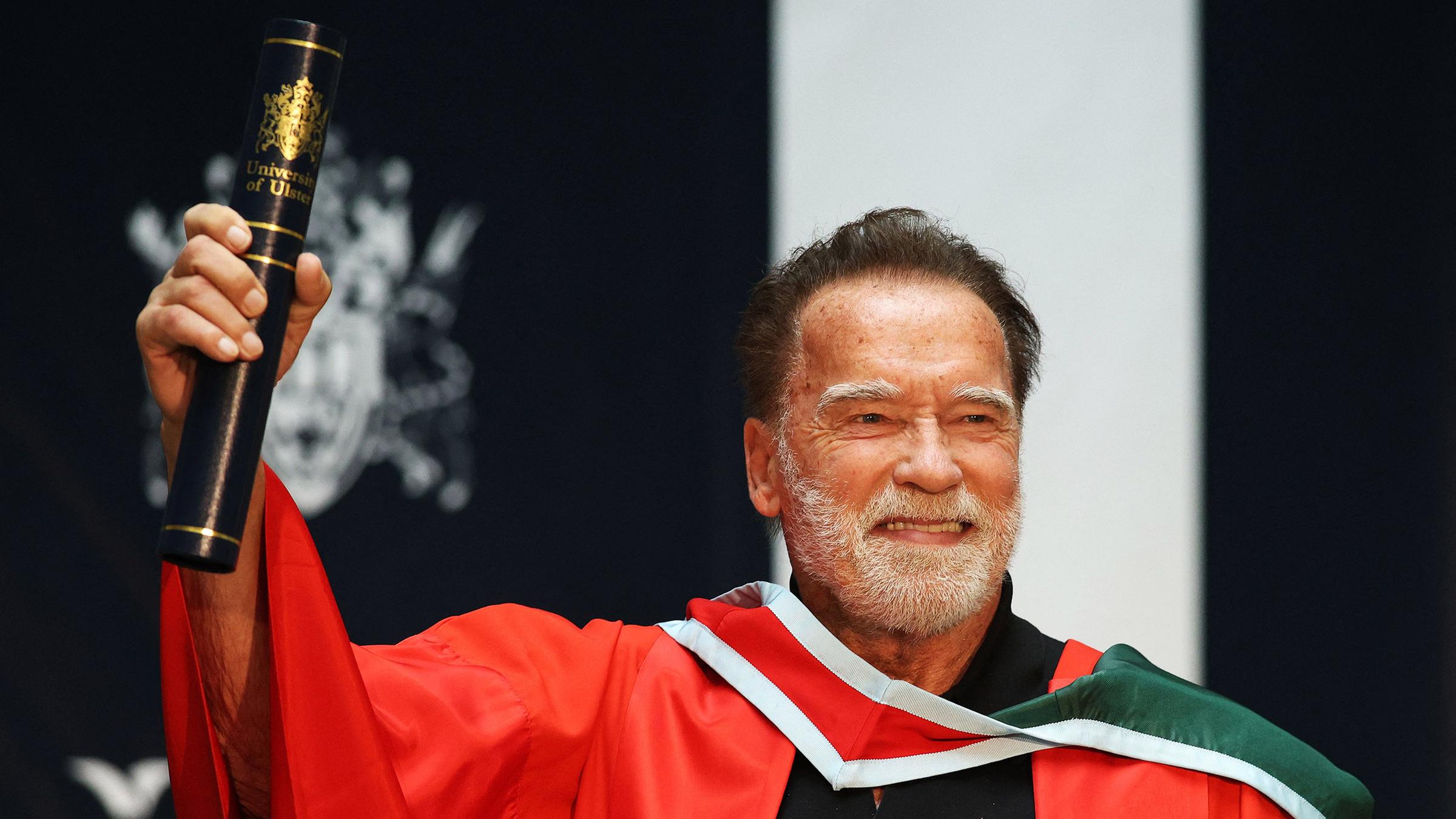 Arnold Schwarzenegger hält sein Doktortitel-Diplom in der Hand.
