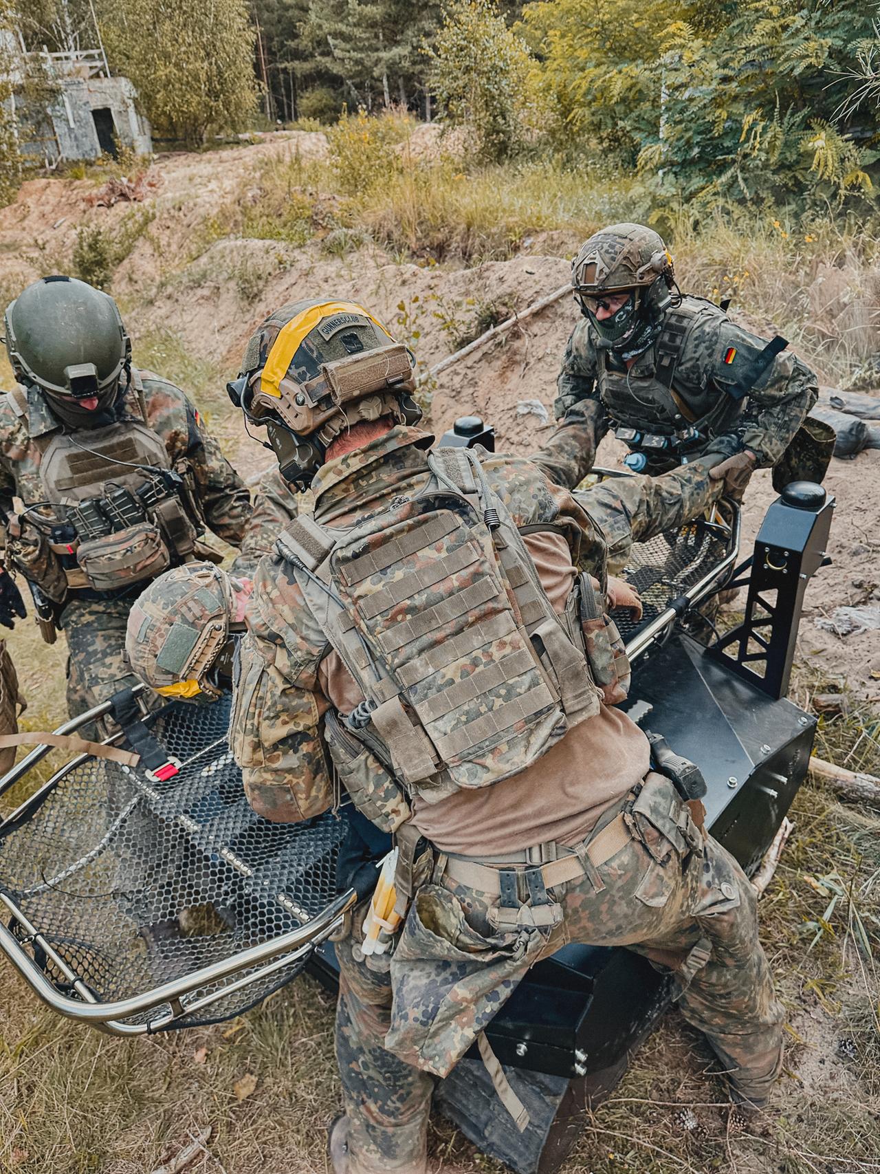 Drei Soldaten stehen neben einem Mini-Panzer. 