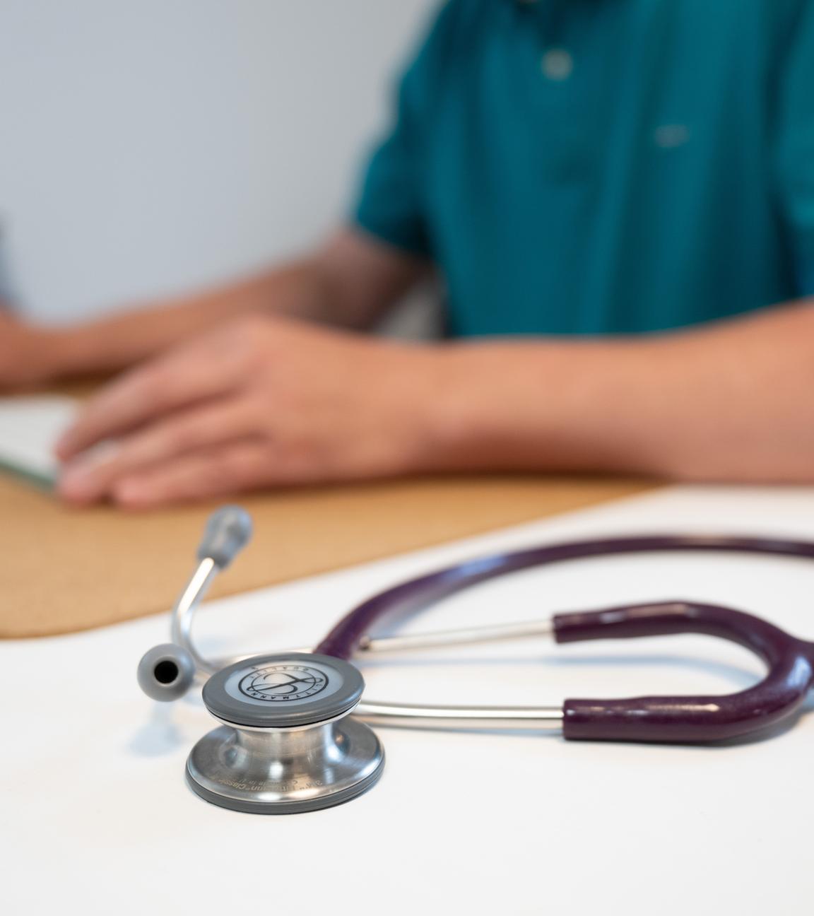 Sachsen, Dresden: Ein Hausarzt sitzt in einem Sprechzimmer seiner Hausarztpraxis an einem Schreibtisch neben einem Stethoskop und arbeitet am Computer.