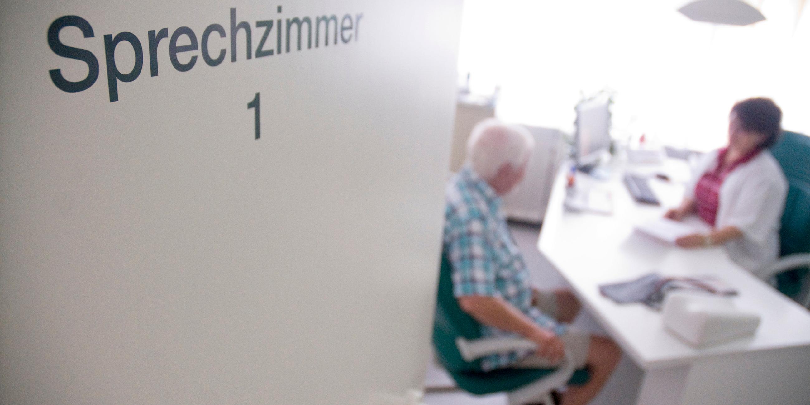 Ein älterer Mann mit weißen Haaren sitzt bei einer Ärztin im Sprechzimmer am Schreibtisch.