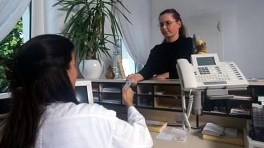 Eine Patientin meldet sich bei der Ankunft in einer Arztpraxis am Empfang