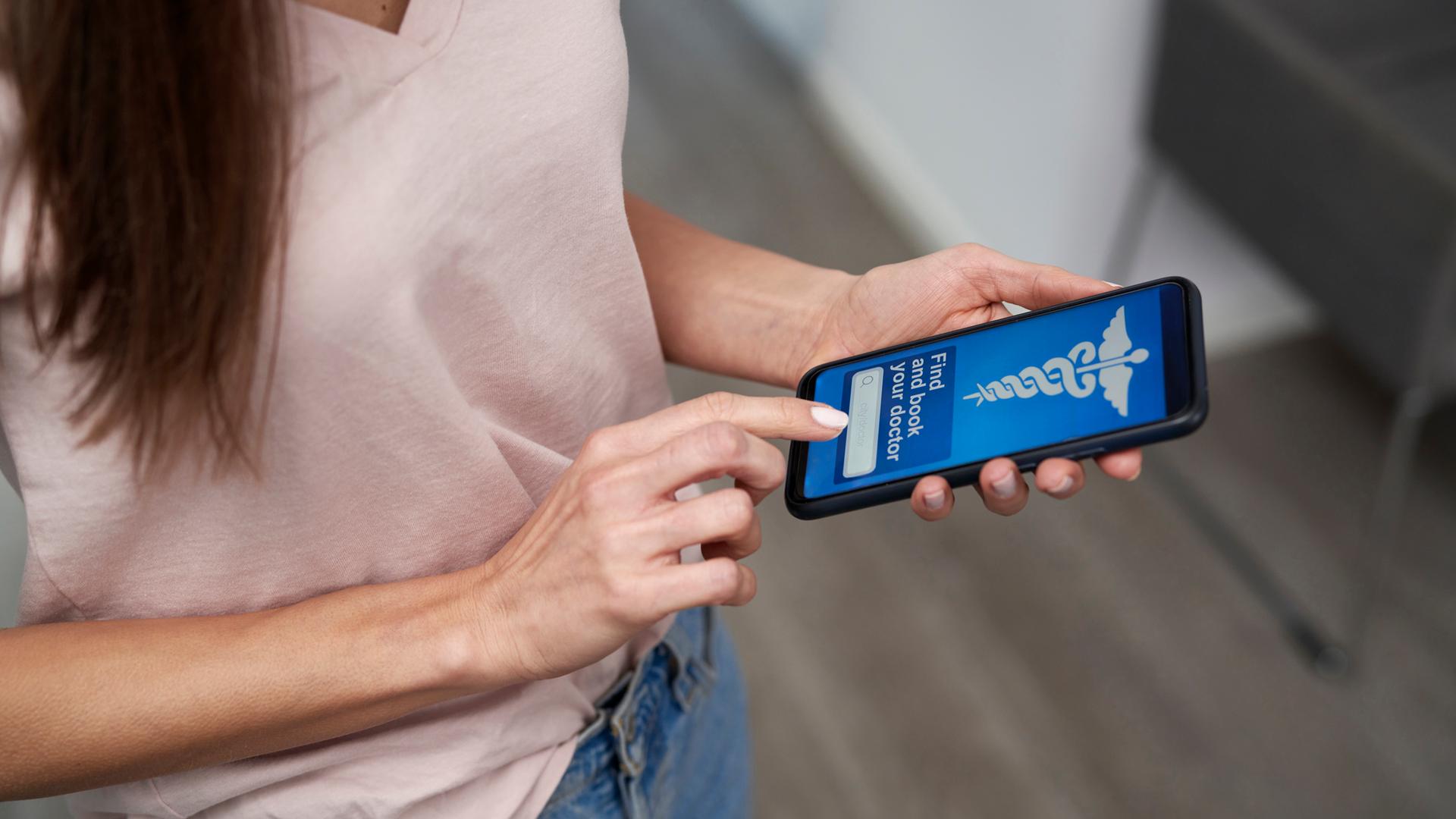 Frau, die in einer Klinik eine App auf ihrem Smartphone benutzt