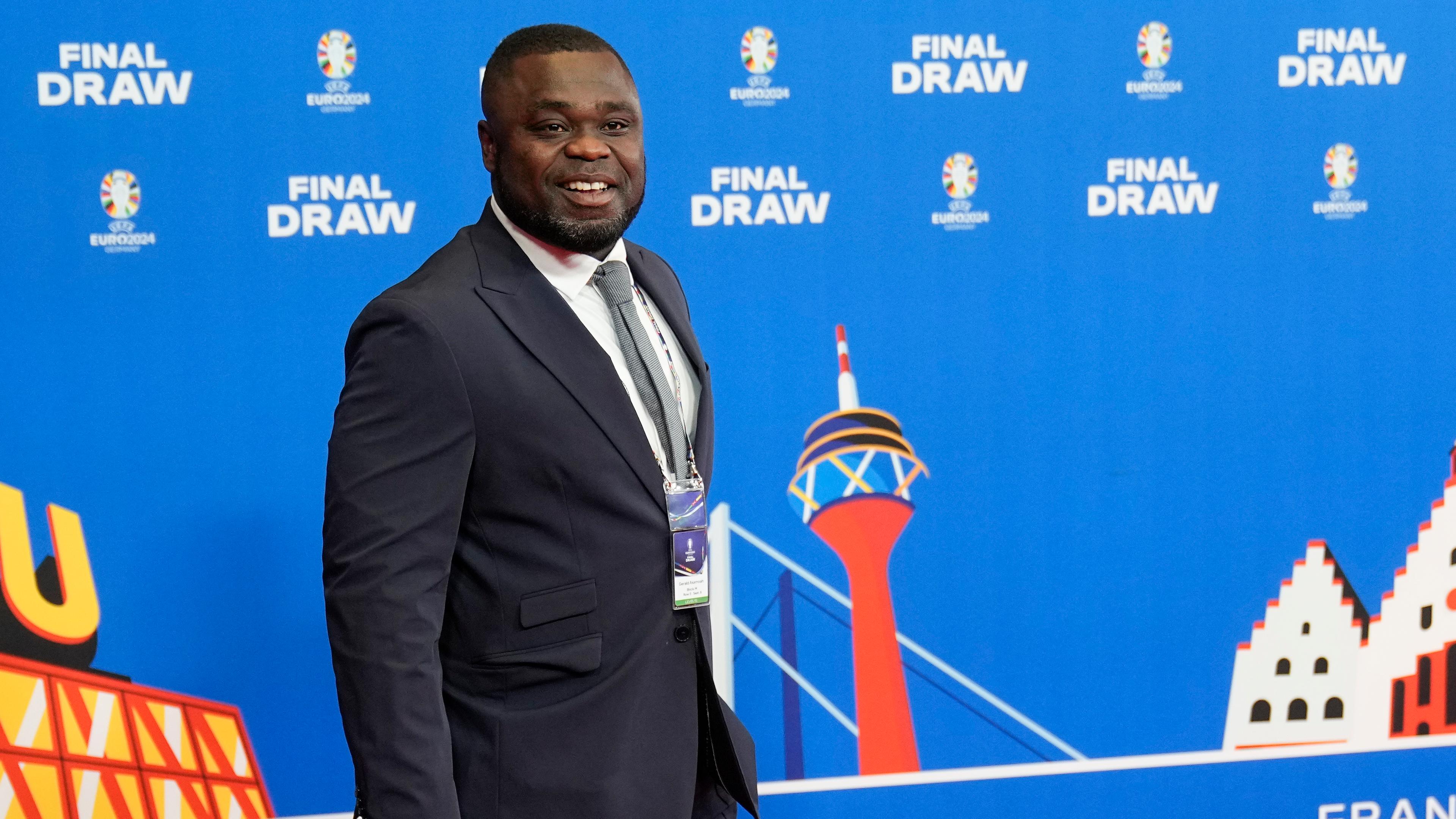 Gerald Asamoah im Anzug vor einer Presswand