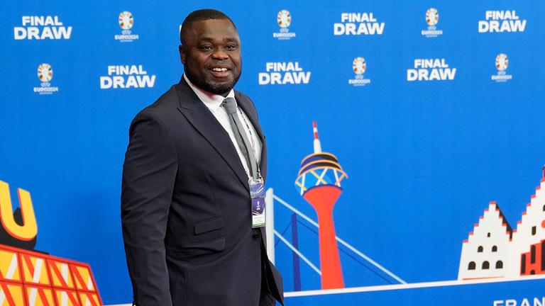 Gerald Asamoah im Anzug vor einer Presswand