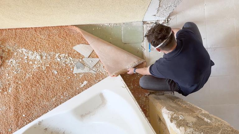 Mann klappt Ecke von Teppichboden zurück