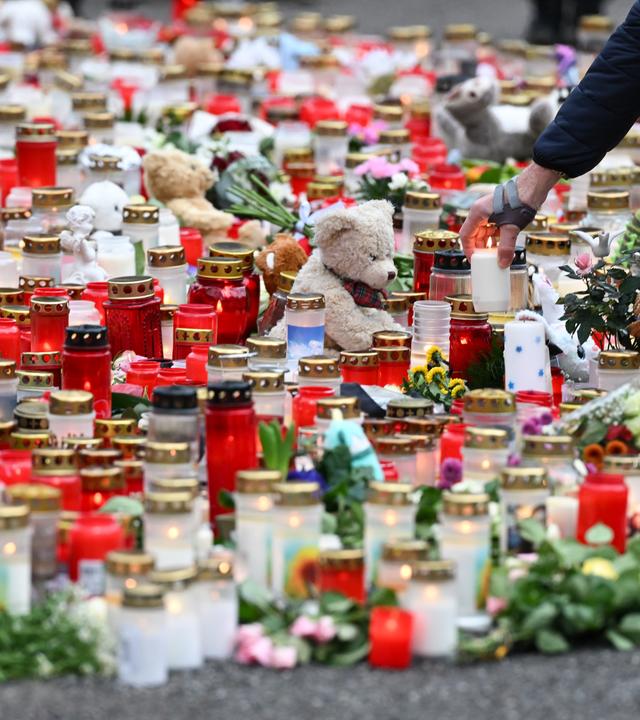 Ein Mann stellt eine Kerze zu zahlreichen anderen Kerzen, Blumen und Plüschtieren im Park Schöntal als Zeichen der Anteilnahme. In dem Park waren am 22.01.2025 ein zweijähriger Junge und ein 41-jähriger Mann bei einem Messerangriff getötet sowie weitere Menschen schwer verletzt worden.