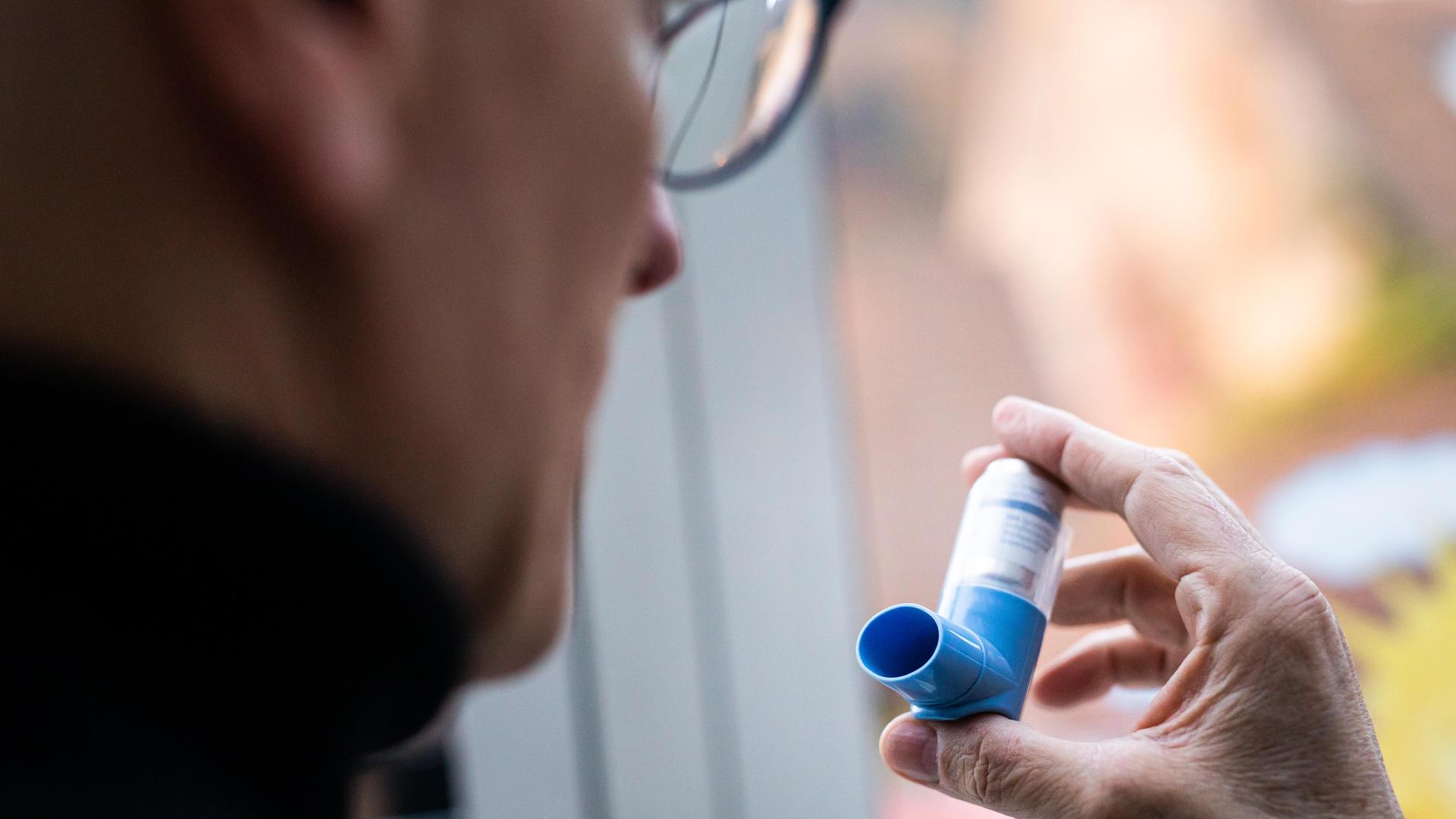Ein Mann hält einen Asthma-Inhalator.