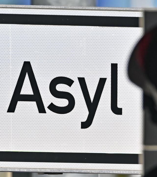 Eine rote Ampel und ein Schild auf dem "Asyl" steht.