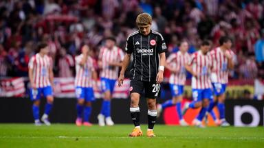 Atletico Madrid - Eintracht Frankfurt: Ritsu Doan steht bedrückt auf dem Platz, während im Hintergrund Atletico-Spieler jubeln.
