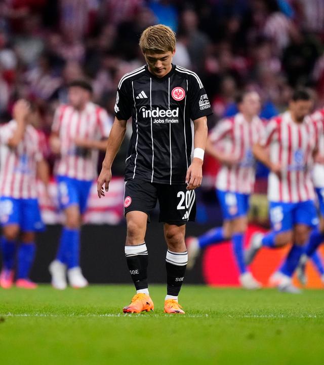 Atletico Madrid - Eintracht Frankfurt: Ritsu Doan steht bedrückt auf dem Platz, während im Hintergrund Atletico-Spieler jubeln.