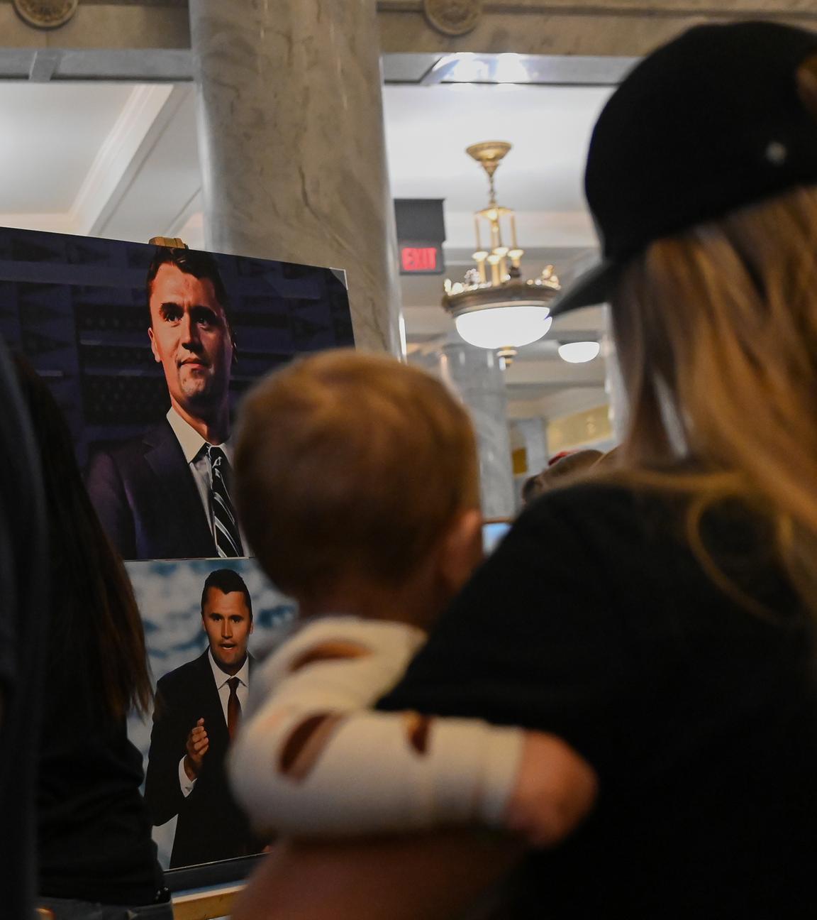  Ein Foto des getöteten rechtskonservativen Podcasters Charlie Kirk steht im Utah State Capitol, davor steht eine Frau mit einem Baby auf dem Arm.