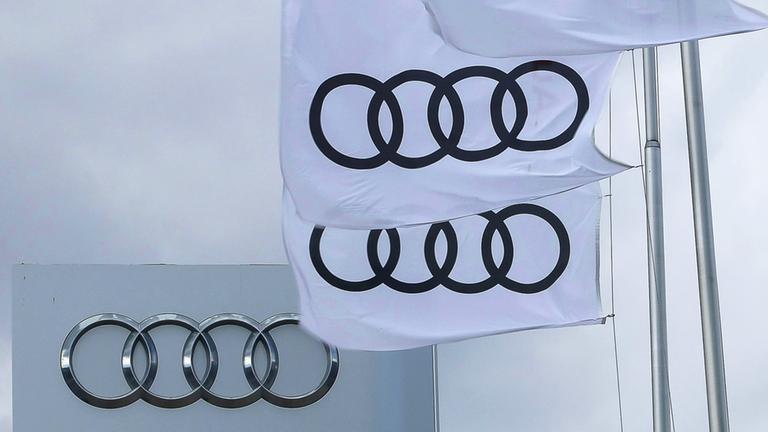Bayern, Ingolstadt: Dunkle Wolken sind hinter Fahnen mit dem Logo von Audi vor dem Audi-Forum zu sehen.