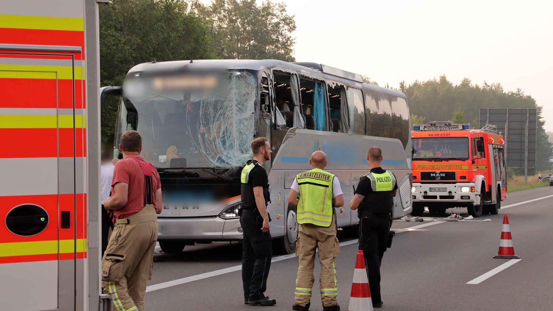 Rettungskräfte stehen neben einem beschädigten Reisebus auf der Autobahn 24. 