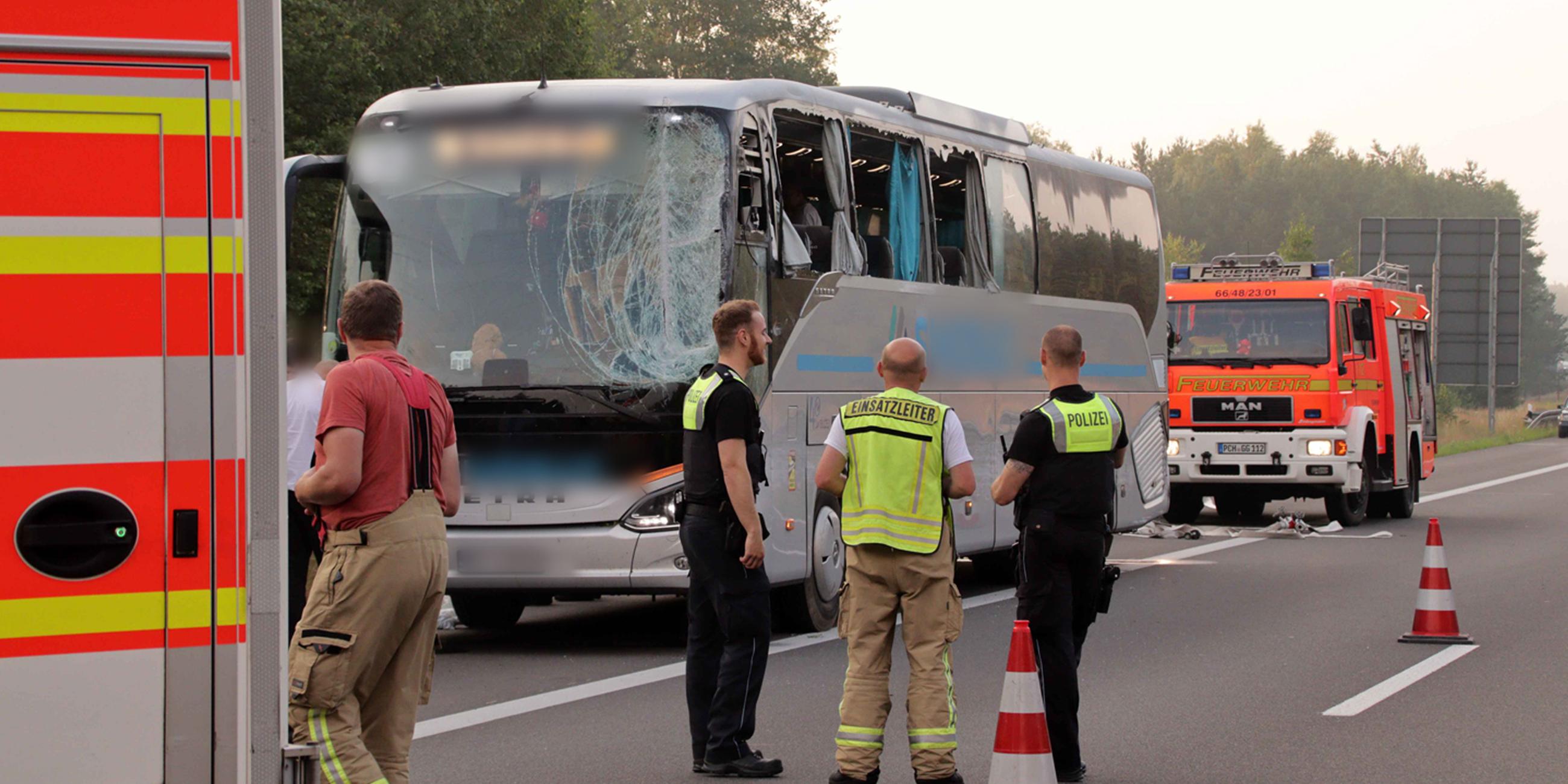 Rettungskräfte stehen neben einem beschädigten Reisebus auf der Autobahn 24. 