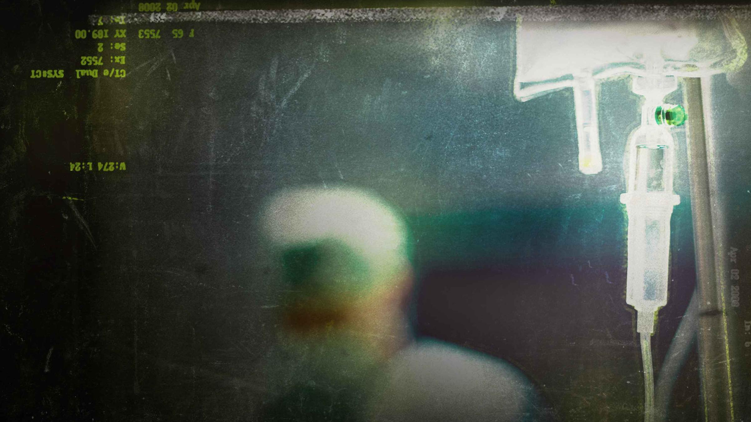 Ein medizinischer Beutel mit angeschlossenem Tropf, im Hintergrund verschwommen der Kopf einer Person in Pflegermontur