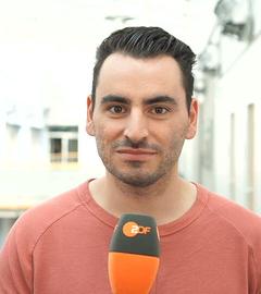 Daniel Heymann aus der Redaktion Recht und Justiz ist mit einem Mikrofon in der Hand zu sehen.