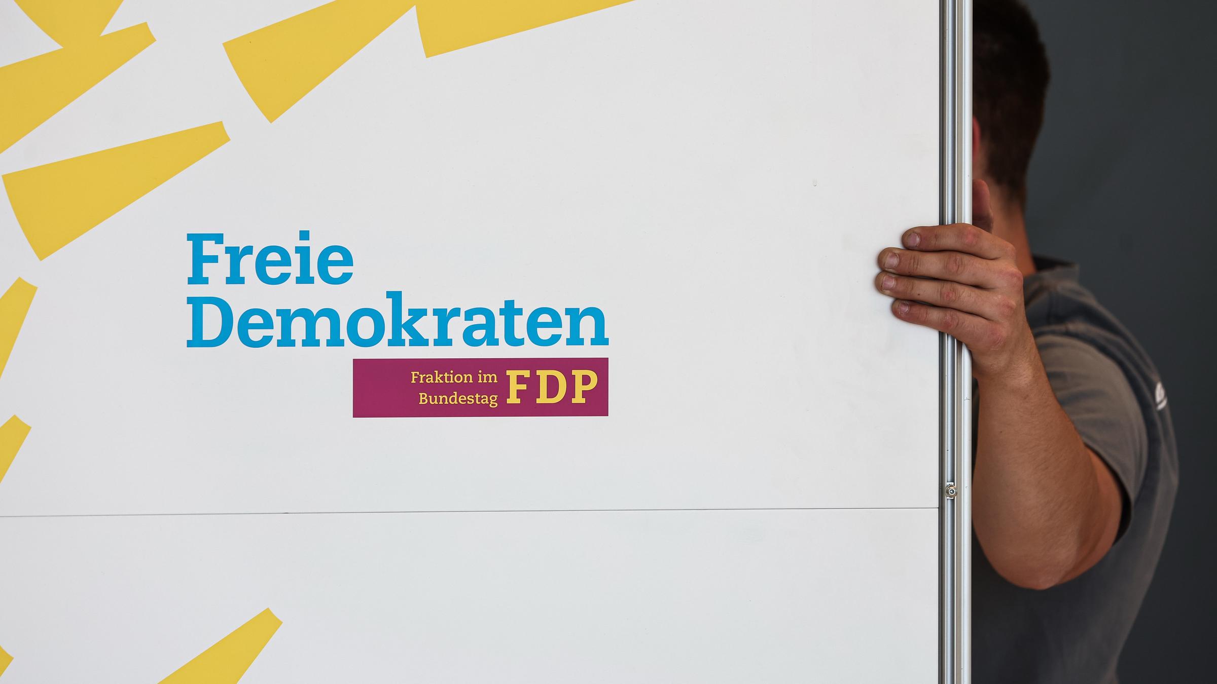 Berlin: Handwerker demontieren einen Aufsteller der FDP im Bundestag.