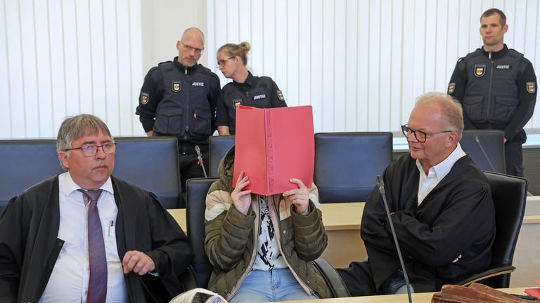 Mecklenburg-Vorpommern, Rostock: Andreas Ohm (l-r), Anwalt, die Angeklagte und Thomas Löcker, Anwalt, warten im Saal des Landgerichts auf den Beginn des Mordprozesses im Fall Fabian. 