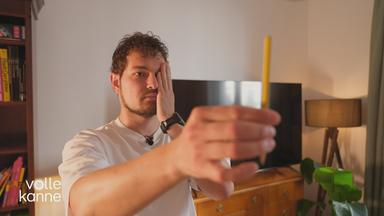 Mann hält sich ein Auge zu und schaut auf einem Stift in der anderen ausgestreckten Hand.