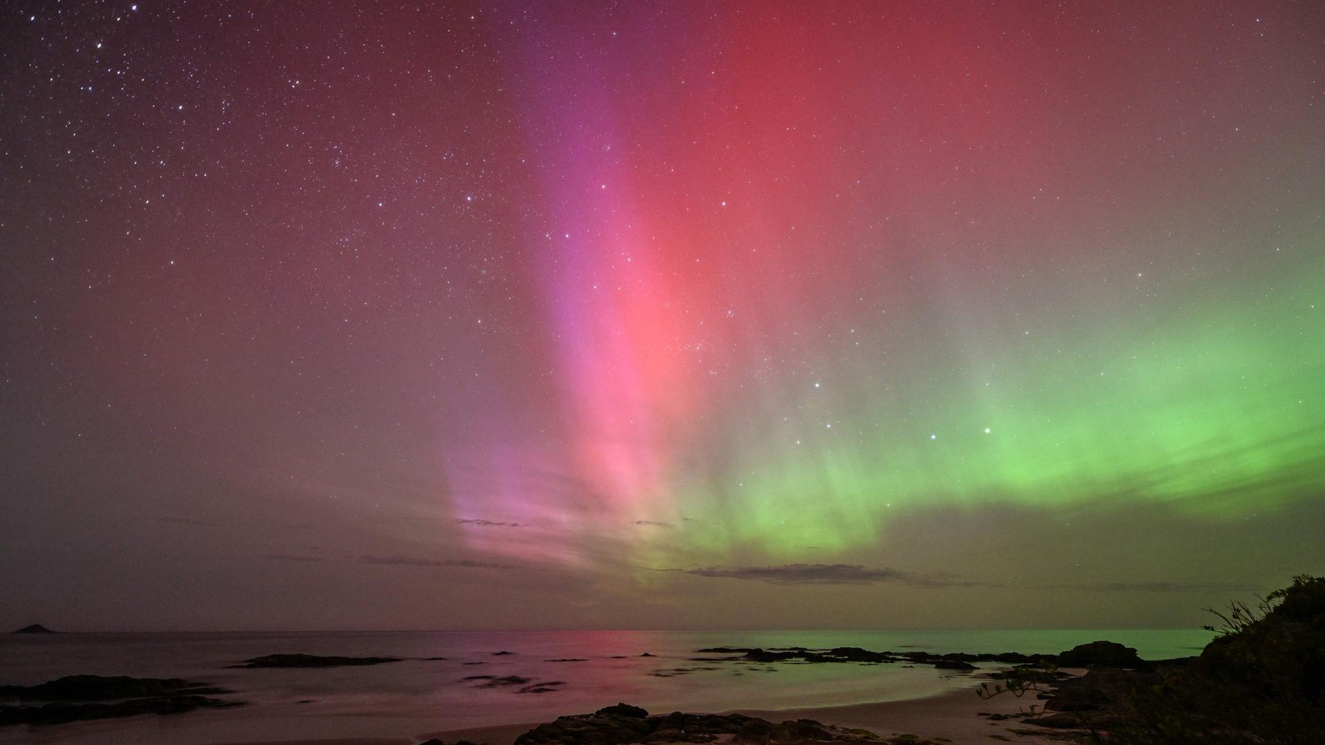 Neuseeland: Aurora Australis, auch bekannt als Südlichter, die am Horizont über dem Wasser von Blackhead Beach in Dunedin leuchten.