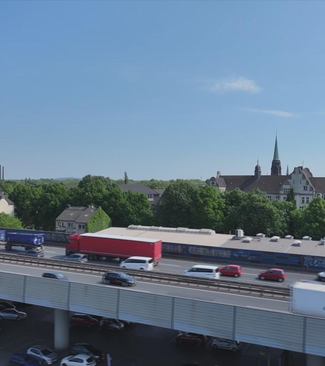 Stark befahrene Autobahnbrücke führt durch Wohngebiet.