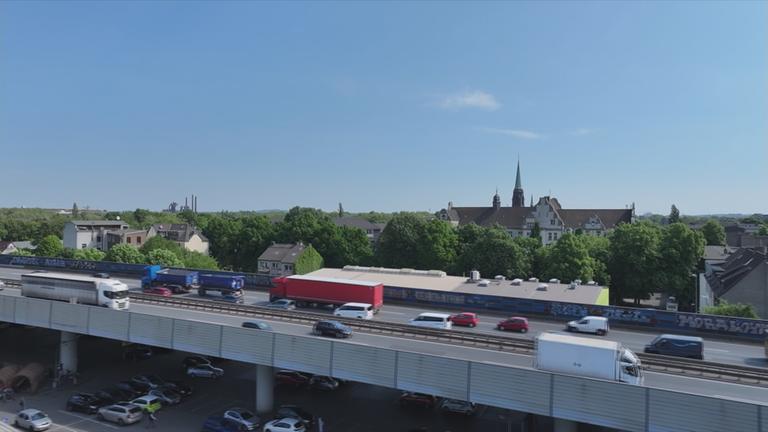 Stark befahrene Autobahnbrücke führt durch Wohngebiet.