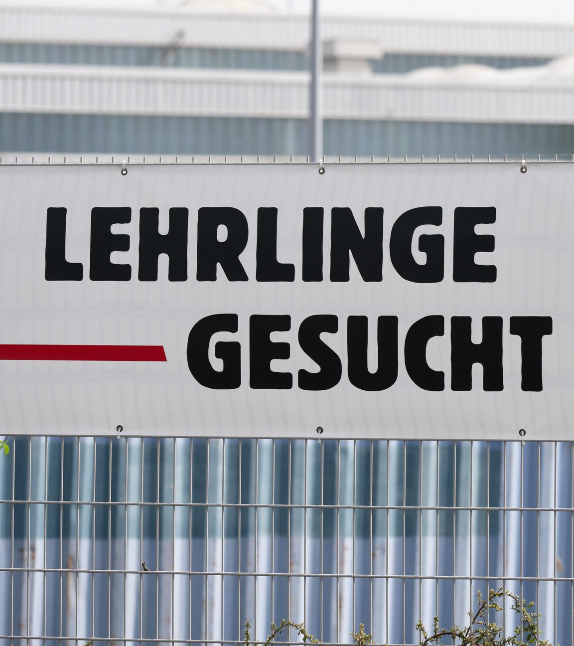Ein Banner mit der Aufschrift Lehrlinge gesucht hängt an einem Zaun.