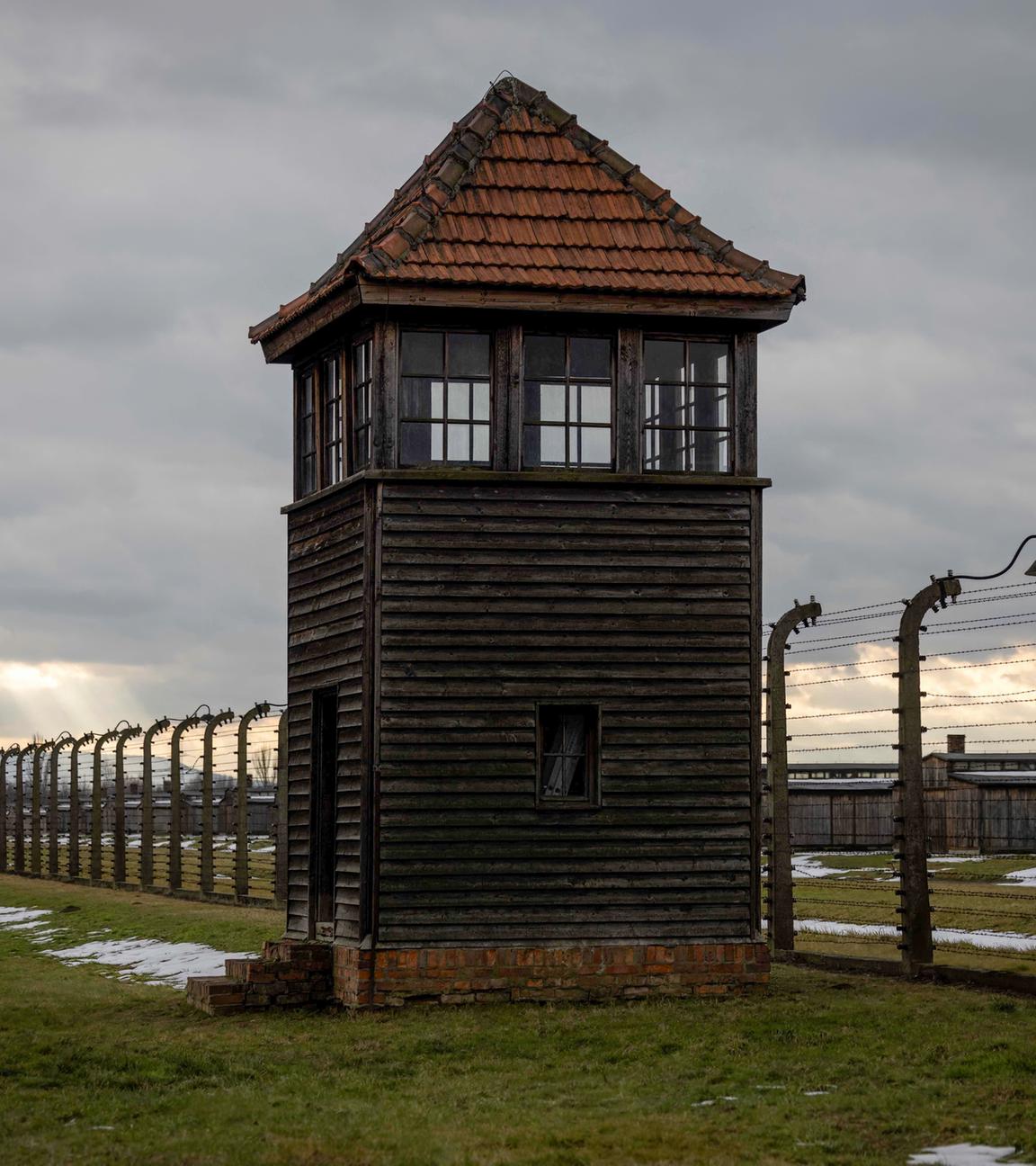 Der Stacheldraht-Zaun vor dem Konzetrationslager Auschwitz mit einem Wachturm.