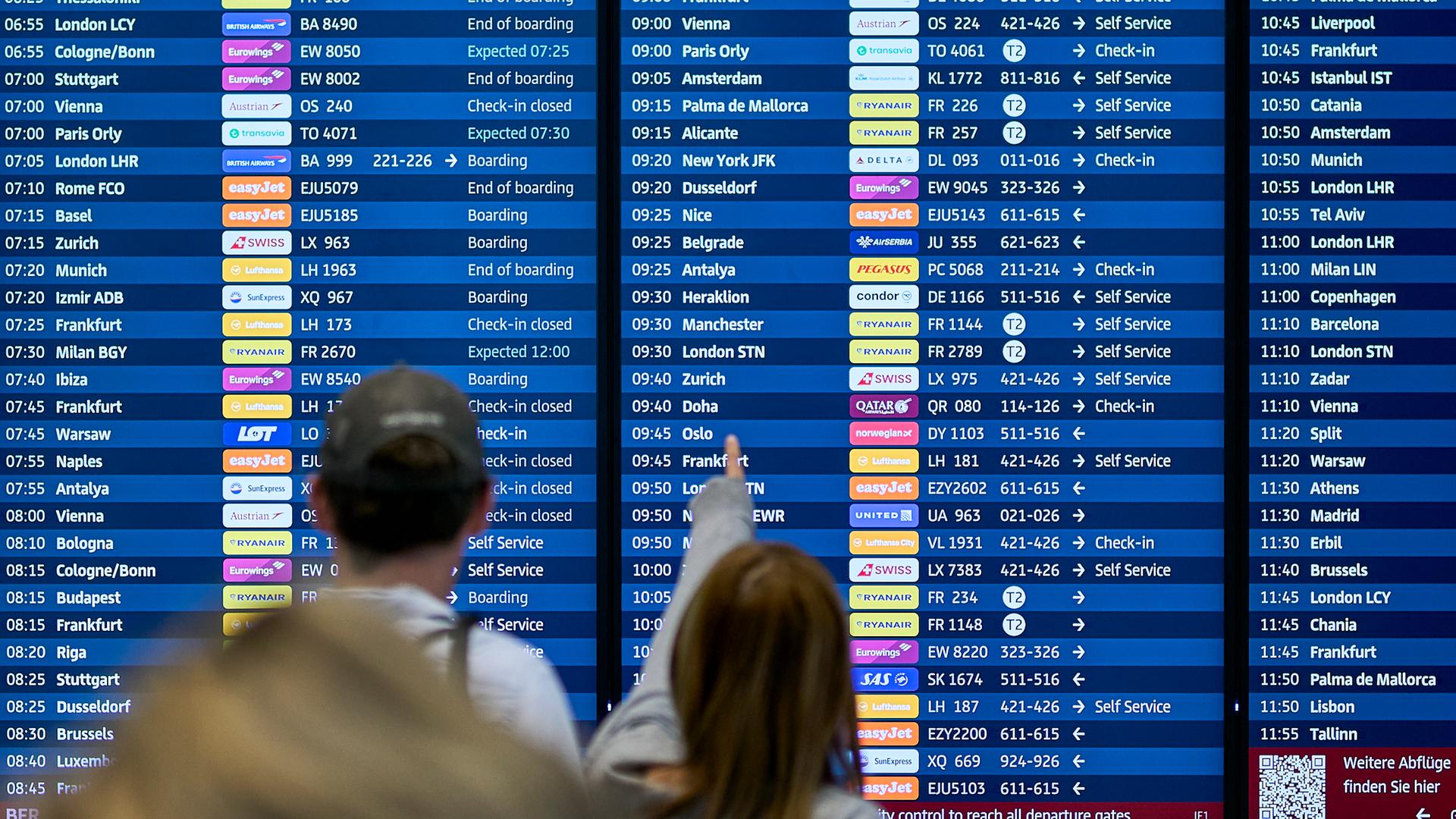 Fluggäste informieren sich an den Abflugtafeln im Terminal 1 des Flughafens Berlin Brandenburg.