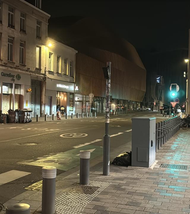 Eine Starße in Lille, Frankreich, bei Nacht. Eine Ampel zeigt grün. Die Straße ist menschen und autoleer.