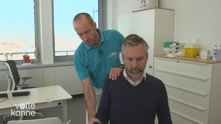 Ein Arzt behandelt die Schulter eines Mannes. 