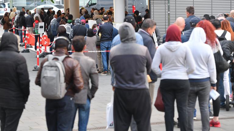 Zahlreiche Menschen stehen am Eingang der Ausländerbehörde in Frankfurt am Main (Hessen) Schlange. Archivbild