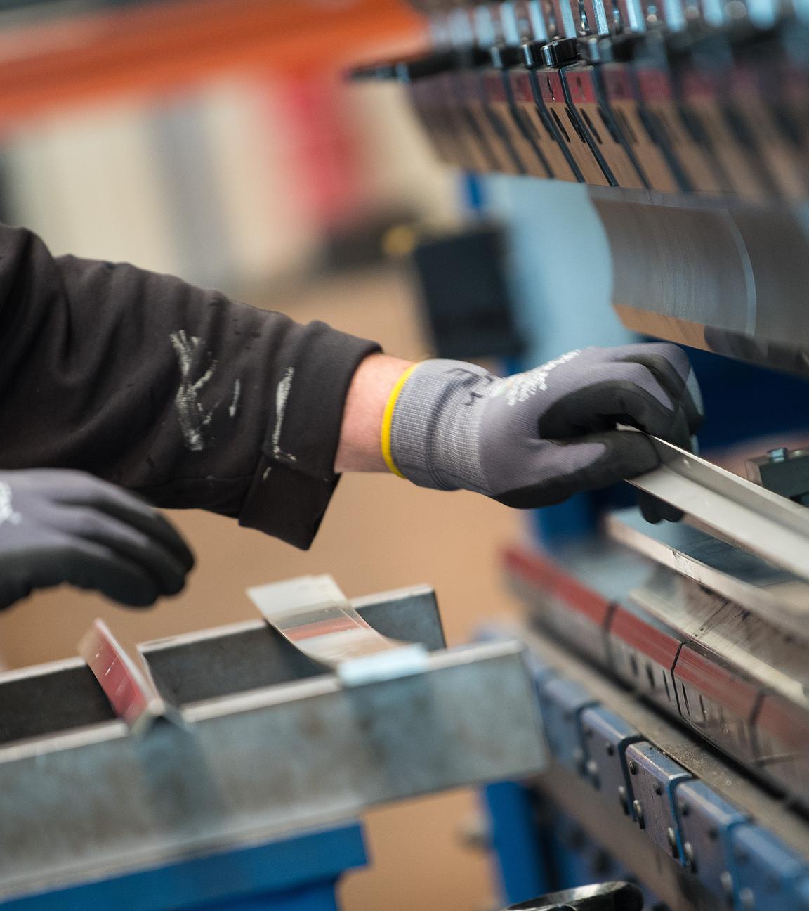 Bandenburg, Esterwerda: Ein Mitarbeiter bedient in der Produktionshalle einer Firma eine Metallpresse. 