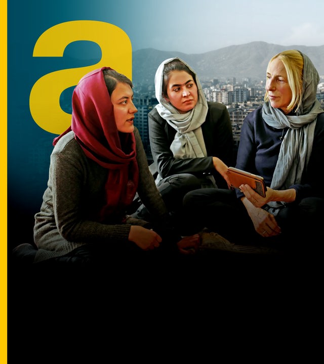Krisenreporterin Katrin Eigendorf blickt hinter die Fassade des Taliban-Regimes. Sie hält ein Handy in der Hand und spricht mit zwei betroffenen Frauen, mit denen zusammensitzt.