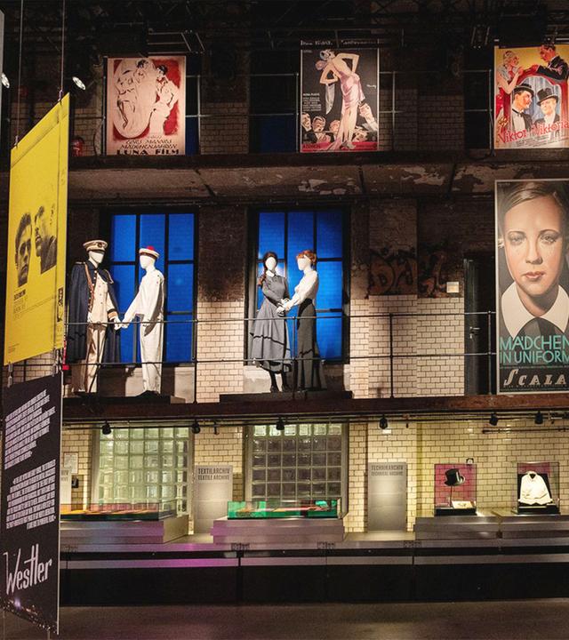 In einem Ausstellungsraum sieht man Filmplakate und Schaufensterpuppen mit Kostümen.