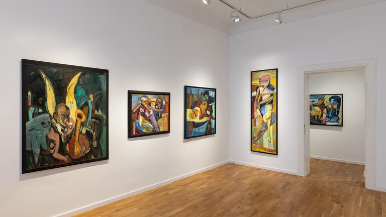 In einem Ausstellungsraum hängen moderne Gemälde an der Wand.