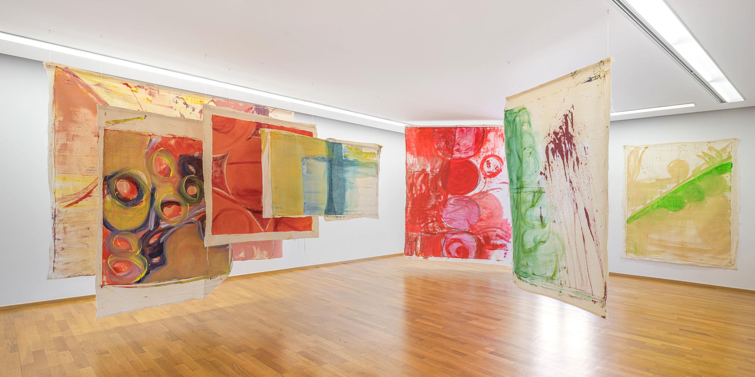 In einem Ausstellungsraum sind bunte, moderne Kunstwerke ausgestellt.