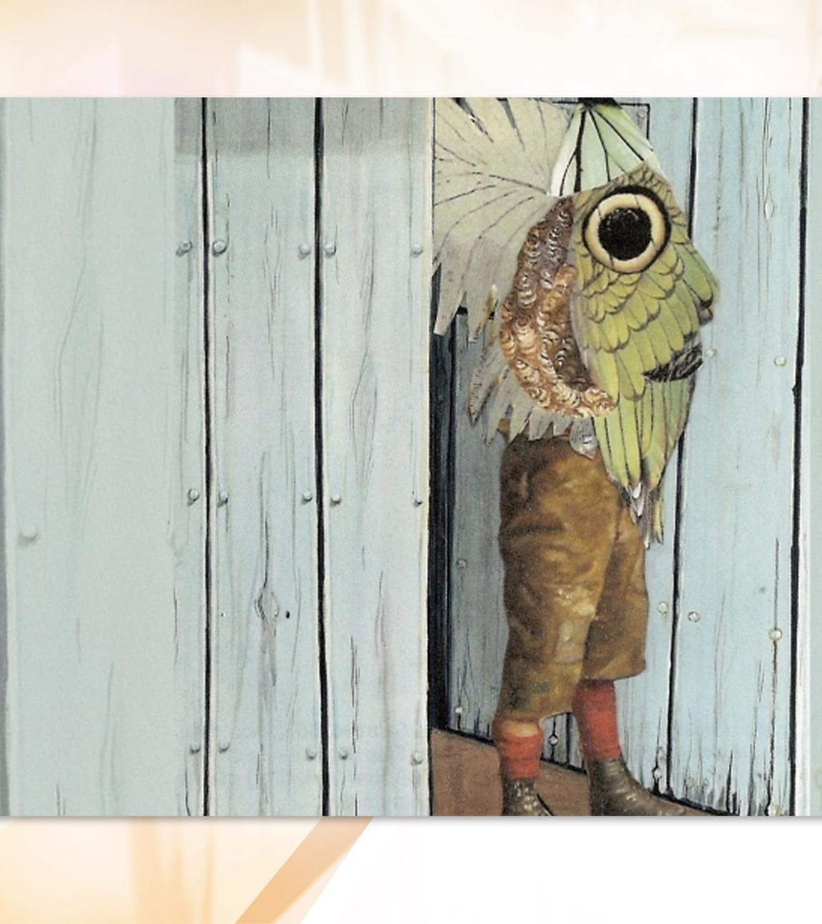 Man sieht eine Person in Lederhosen, die vor einer Holzwand steht. Sie trägt eine Art großen Schmetterlingsflügel der ihren Oberkörper bedeckt.