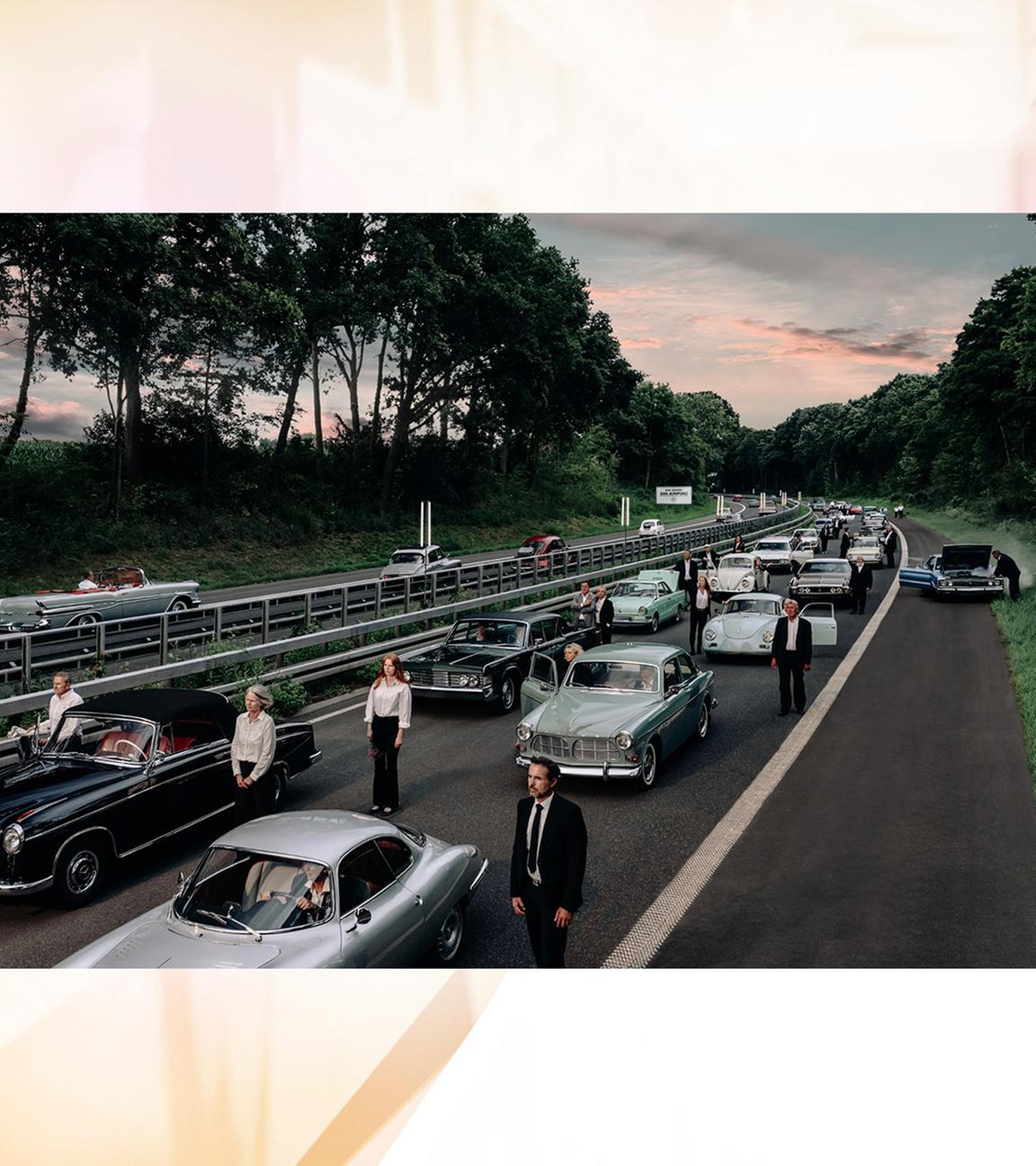 Auf einer Aotobahn stehen Autos im Stau und Menschen drumherum. Sie schauen alle in eine Richtung.