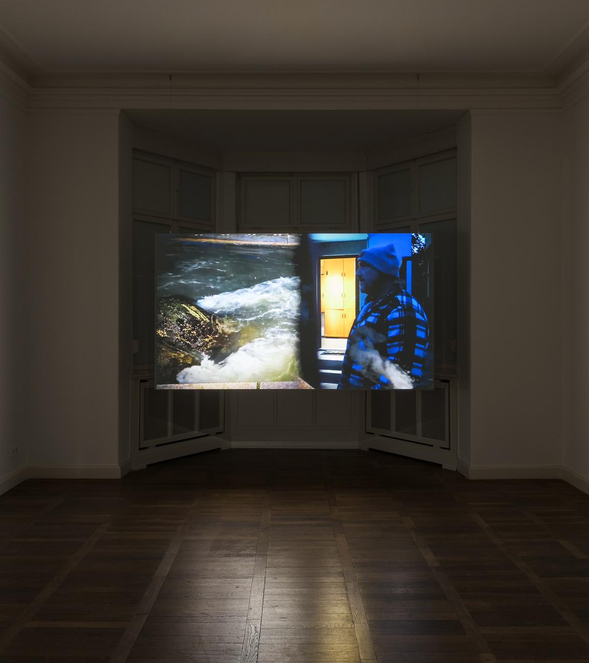 In einem abgedunkelten Ausstellungsraum sieht man ein erleuchtetes, modernes Kunstwerk in Blau - und Gelbtönen an der Wand.