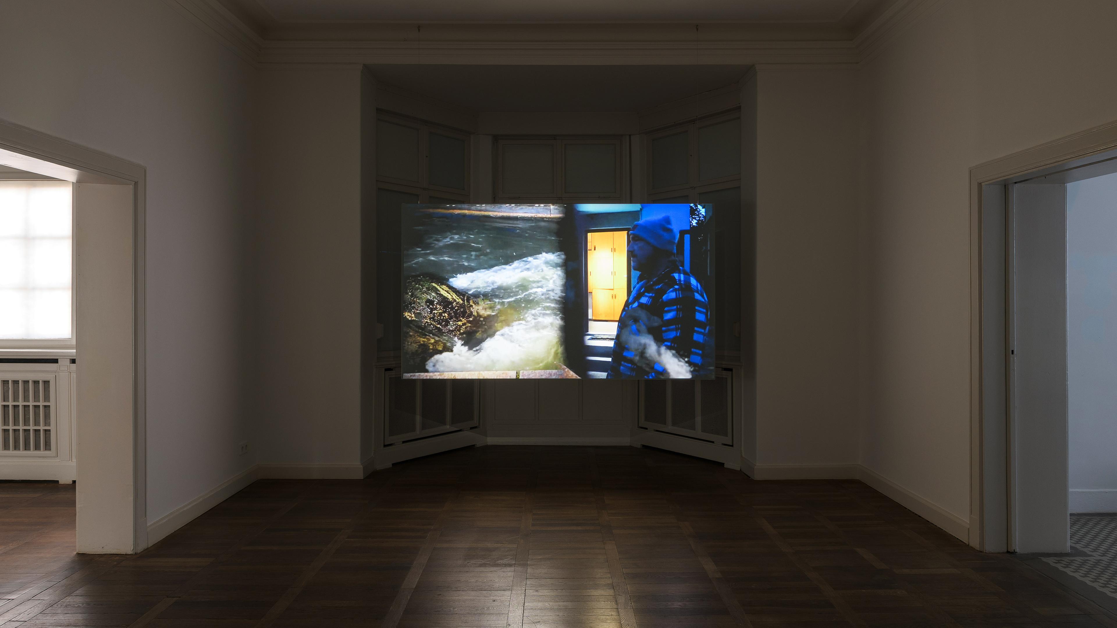 In einem abgedunkelten Ausstellungsraum sieht man ein erleuchtetes, modernes Kunstwerk in Blau - und Gelbtönen an der Wand.