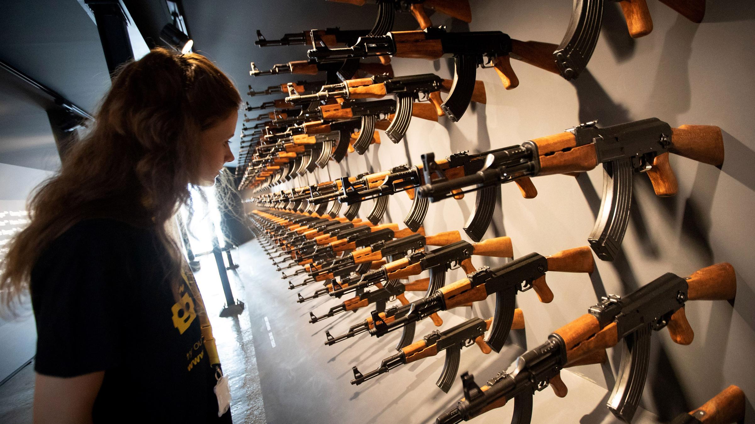 Eine Besucherin steht vor einer Installation aus 140 Kalashnikow-Gewehren