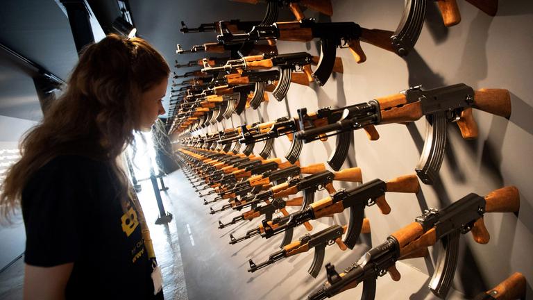 Eine Besucherin steht vor einer Installation aus 140 Kalashnikow-Gewehren